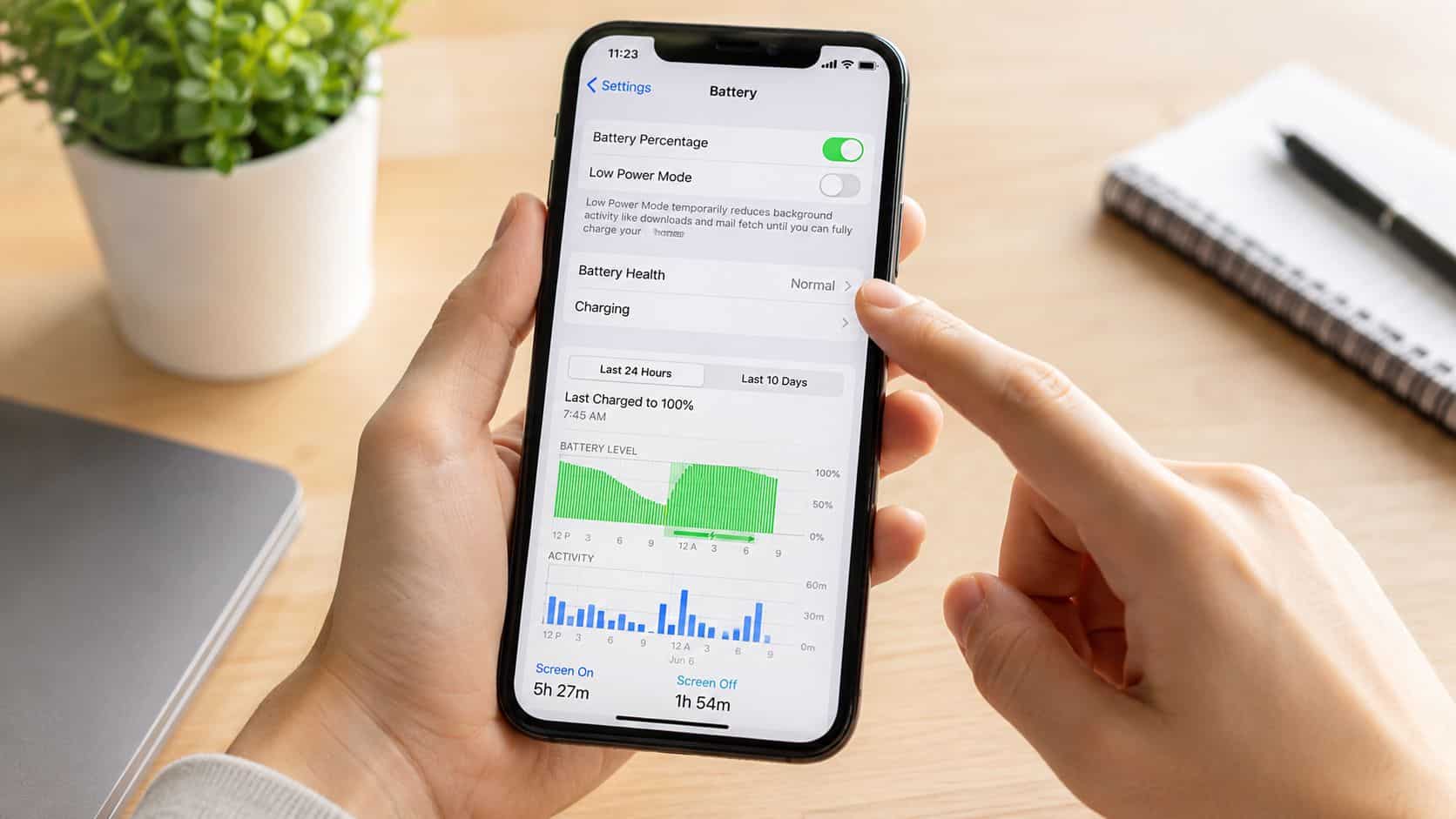 A person holding an iPhone displaying the battery settings menu showing usage statistics and health status.